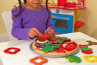 a girl using a melissa & doug pizza