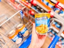 A can of Progresso soup held up over Walmart shopping cart