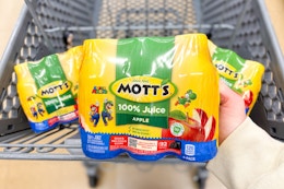 hand holding motts juice over shopping cart