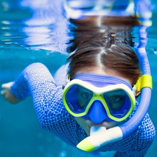 child under water with a snorkeling kit on face
