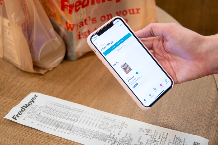 A person holding a smartphone above a receipt to take a photo for the ibotta rebate app.