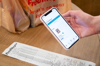 A person holding a smartphone above a receipt to take a photo for the ibotta rebate app.