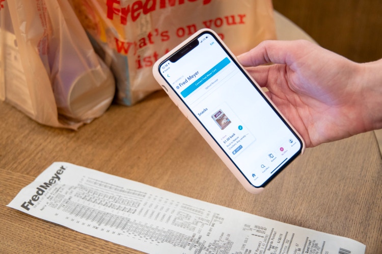 A person holding a smartphone above a receipt to take a photo for the ibotta rebate app.