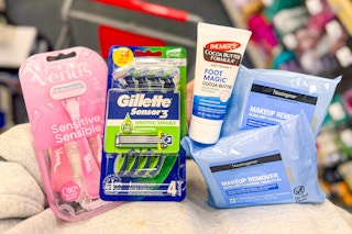 person holding neutrogena makeup wipes, palmers foot cream, and gillette and venus razor packs
