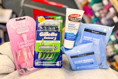 person holding neutrogena makeup wipes, palmers foot cream, and gillette and venus razor packs