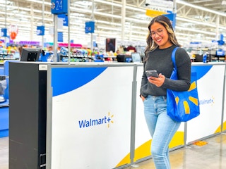 a woman holding a cell phone walking next to a walmart plus sign in store 