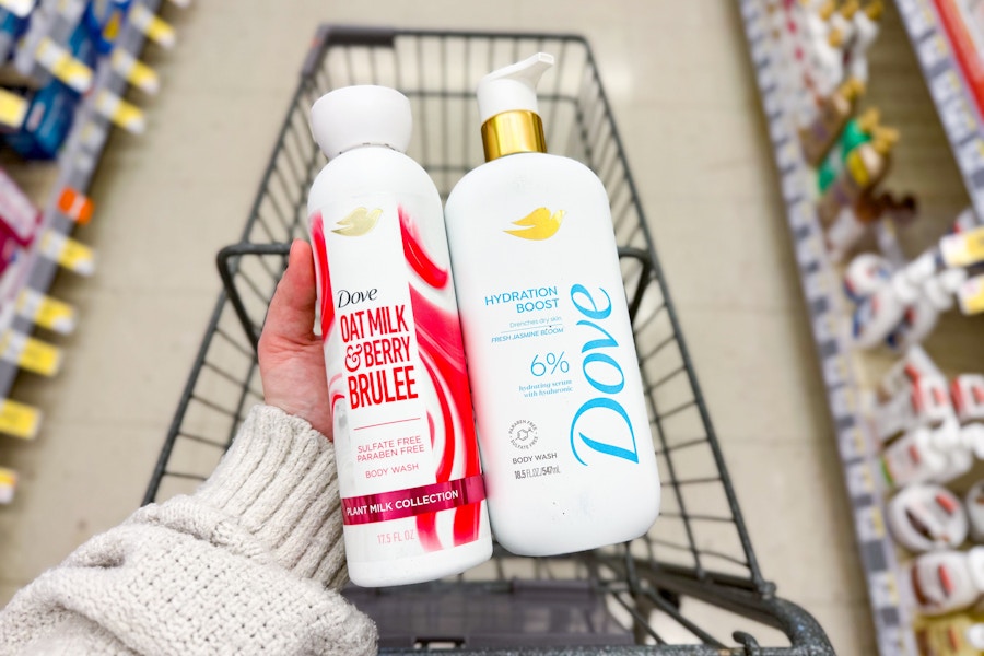 person holding 2 dove body washes over a cart