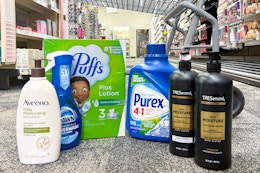 aveeno lotion, dawn powerwash, puffs tissues, purex detergent, and tresemme shampoo on the floor in front of a cart
