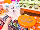 hand holding a ghost snackle box in front of halloween items at target