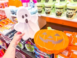 hand holding a ghost snackle box in front of halloween items at target