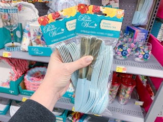 two packs of the pioneer woman plastic cutlery held up in front of party supplies