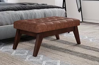 Lifestyle image of the Distressed Saddle Brown of the Simpli Home Ottoman in home setting