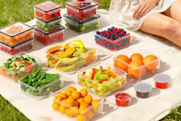 food in storage containers on a picnic blanket outside 