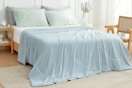 A bed is partially covered by a light blue queen size cooling blanket.
