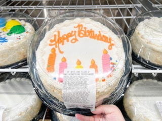 a person grabbing a round costco birthday cake