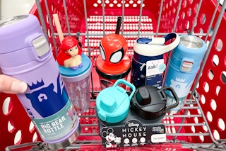 hand holding a stanley bottle over a target cart with other drinkware