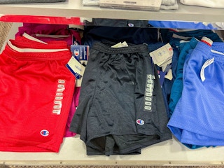 Red, black, and blue Champion shorts folded on a shelf