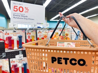 hand holding Petco basket in front of sale sign