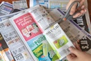 hands with scissors cutting out Go-GURT coupon from newspaper