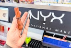 person holding nyx butter gloss and lip liner in front of the display