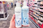 person holding ouidad shampoo and conditioner in an aisle