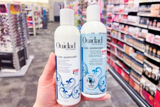 person holding ouidad shampoo and conditioner in an aisle