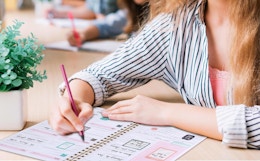 a person writing in a planner at a desk