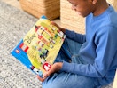 A child excited to be holding a disney lego set while sitting on the floor.