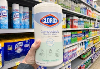 clorox compostable disinfecting wipes being held with left hand in front of disinfectant spray shelf at walmart