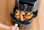 a woman opening up an air fryer