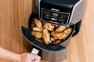 a woman opening up an air fryer