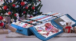 wrapping paper and ribbon rolls in a blue bag in front of a Christmas tree 
