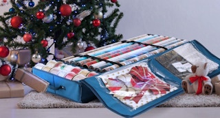 wrapping paper and ribbon rolls in a blue bag in front of a Christmas tree