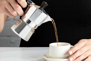a person pouring coffee in to a mug