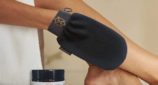 person using korean skincare exfoliating mitt on their legs