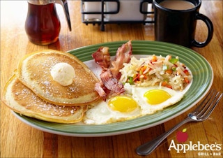 Pancakes, bacon, two eggs suny side up, and potato hash on a plate at Applebee's