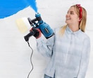 a woman holding a paint sprayer that's spraying blue paint