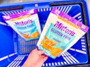 hand holding a bag of miltons crackers over another bag in walmart hand cart