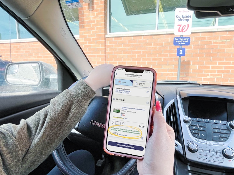 woman sitting in car at walgreens curbside pick up holding cellphone 