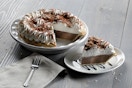 A slice cut from a pie sitting on a table next to the rest of the pie and a fork