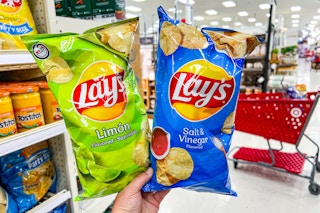 hand holding two bags of Lay's potato chips
