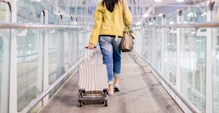 a person rolling a suitcase at an airport