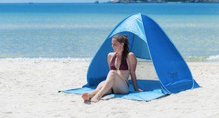 woman sitting under blue cabana at the beach