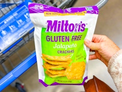 hand holding a bag of milton-s jalepeno crackers over walmart cart