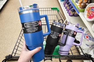 person holding a blue tumbler with black and purple tumblers in a cart