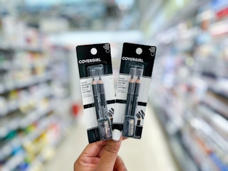 hand holding two covergirl eyebrow pencils