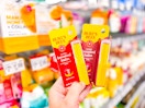 hand holding two packages of Burt's Bees boosted balm