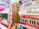 a hand holding a box with mascara in front of a store display