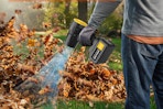 Man using the Ceshu 2 X 4.0Ah Battery Handheld Leaf Blower on leaves outdoors.