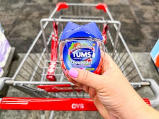 person holding tums chewy bites over a cvs cart